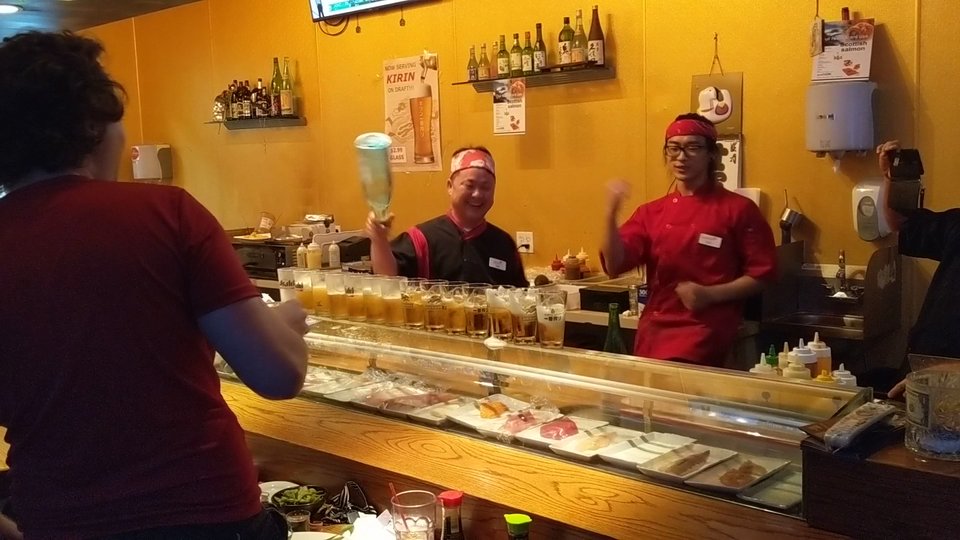A sushi counter with bar seating nearby.